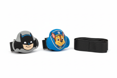 Two BuckleBuddeez infant car seat chest clip covers displayed face-up on a white surface beside a folded harness strap, showing Batman and Paw Patrol Chase character illustrations