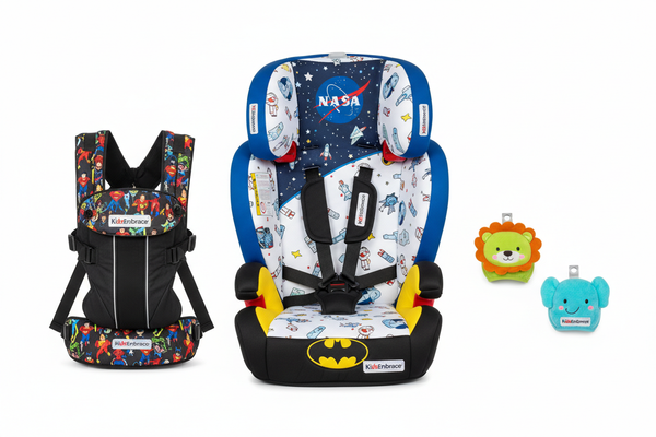 Studio flat-lay of all four KidsEmbrace Family Safety Bundle components on white background: BuckleBuddeez infant clip set, NASA Astronaut 2-in-1 Harness Booster, Batman High Back Booster, and Justice League Baby Carrier, styled as a premium gift set with KidsEmbrace branding visible
