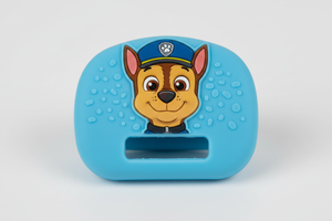 Close-up macro detail of a single BuckleBuddeez clip showing soft elastomeric grip texture, Paw Patrol Chase character-illustrated face, and the strap channel opening that slides over existing harness webbing
